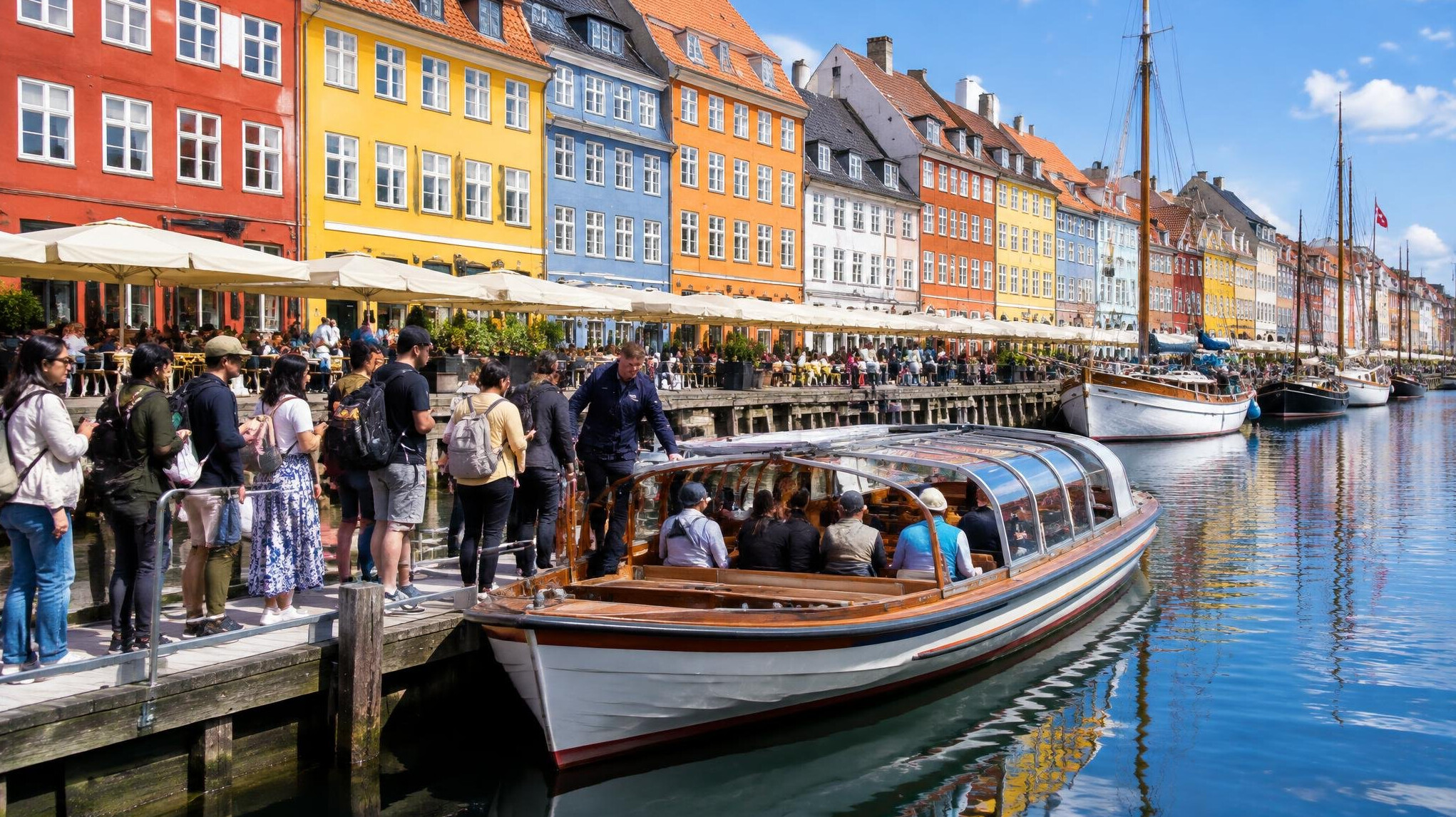 Colorful Nyhavn harbor houses with visitors queuing for a canal boat tour