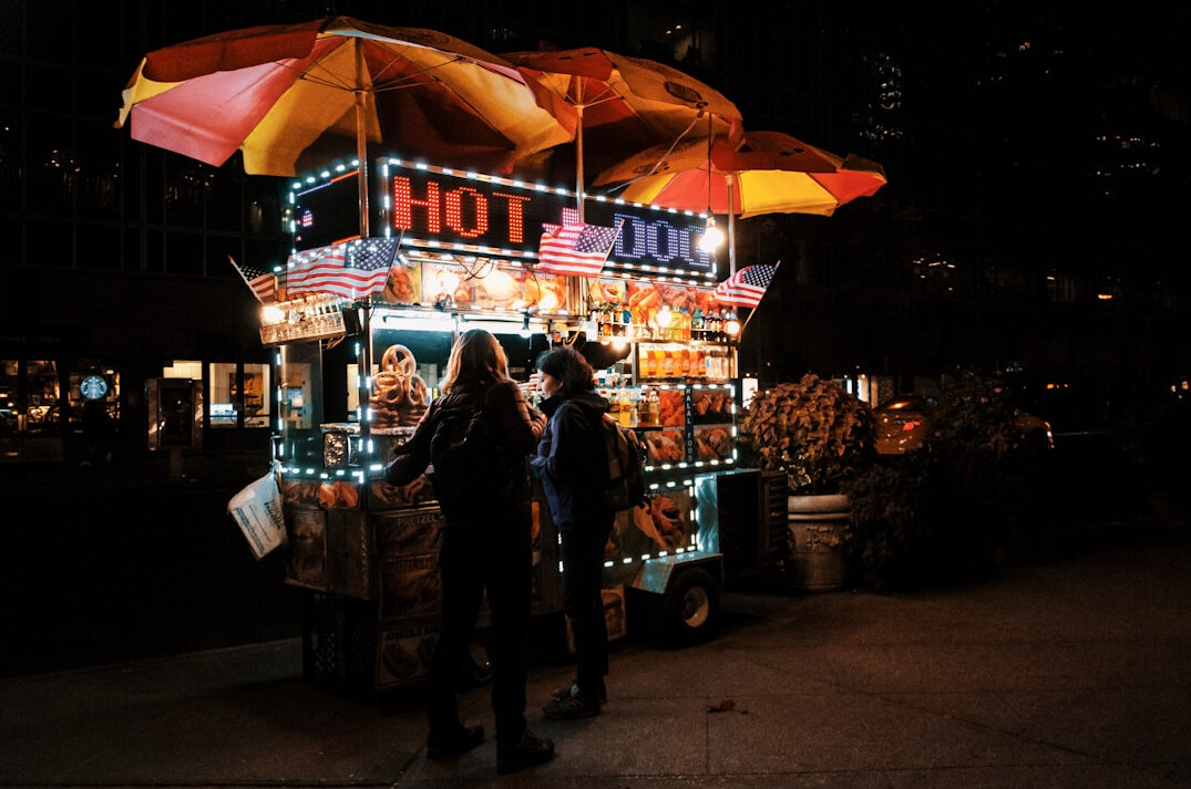Danish hot dog cart with a short queue of customers on a city street
